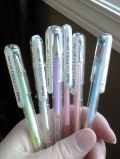 a person is holding six pens in their hand and they are all lined up with writing on them