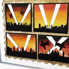 four paintings are hanging on a wall in the shape of cityscapes with airplanes flying over them