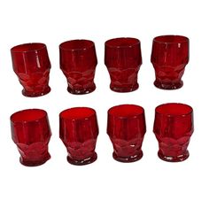 a set of nine red glasses sitting next to each other