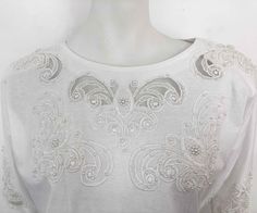 "The Age of Innocence has returned with this white cotton jersey beyond basic tee that is emblazoned with cut out lace floral embroidery x peek a boo see through lace details w/ pearls. Set with shoulder pads. SECTION: WHITE COTTON x COTTAGES MATERIAL: 100% Cotton SIZE: No label- Fits M CONDITION: Excellent Vintage Condition No stains, tears, repairs, rips or holes. ✂ - - - MEASUREMENTS: Inches Chest Width: 22\" Hem Width: 22\" Neck Width: 9\" Sleeve Length: 26\" Length (HPS-high point shoulder White Embellished Crew Neck T-shirt, White Embellished Crew Neck Top, White Crew Neck T-shirt With Lace Trim, White Embellished Cotton Tops, Bright Sweater, Fancy Top, The Age Of Innocence, Oversized Sweater Cardigan, Sweet Violets