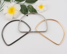 two heart shaped hair pins sitting on top of each other next to flowers and leaves