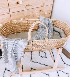 a wicker bassinet with grey and white striped blankets on it, next to a dresser