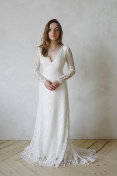 a woman in a white wedding dress standing on a wooden floor with her hands behind her back