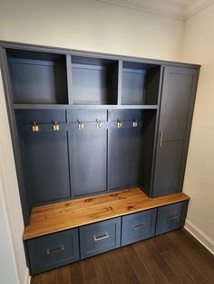 a large wooden bench in the middle of a room with blue cabinets on both sides