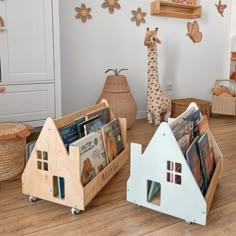 two wooden toy houses and a giraffe on the floor in a child's room