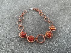 This isn't just a bracelet; it's a bold declaration of style. The Fiesta Nest Bracelet features vibrant marbled red jasper wire wrapped onto handmade copper links. This eclectic necklace looks perfect solo or stacked for a festive everyday look. ## Sizing Total length is adjustable from 6-7 inches ## Materials Every item is 100% handmade and one-of-a-kind. The wire-wrapped raw copper jewelry is oxidized and polished to beautifully highlight details of the wirework. Finally, it's sealed with a pr Unique Copper Bracelets With Natural Stones, Orange Hand Wrapped Bracelet Jewelry, Artsy Bracelet With Unique Variations, Wire Wrapped Copper Bracelet As Gift, Artisan Wire Wrapped Copper Bracelets, Artisan Wire Wrapped Bracelets, Artisan Copper Wire Wrapped Bracelets, Handmade Copper Wire Jewelry With Round Beads, Unique Metal Wire Wrapped Beaded Bracelets