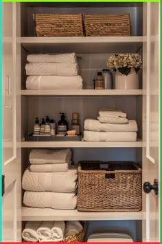 an organized closet with white linens, towels and baskets on the shelve