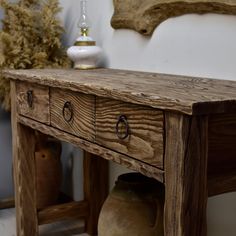 a wooden table with drawers and vases on it