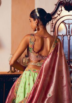 Embrace timeless elegance with this classic kalidar lehenga set, crafted from light green jacquard silk banarasi. Featuring intricate embroidery enhanced with zari and zardozi work, the design is further adorned with dabka, sequins, pearls, and gota texturing. The ensemble includes a heavily embroidered blouse made from pastel pink silk zari tissue, adorned with a floral embroidery pattern and embellished with pearl tassels. Complementing the set is a shimmering pastel pink silk zari tissue dupatta, featuring floral embroidered motifs and a patchwork embroidered border. A signature embellished belt creates a gracefully defined and sophisticated silhouette. Meenakari Raw Silk Pre-draped Saree For Wedding, Silk Lehenga With Meenakari For Reception, Silk Meenakari Choli For Reception, Meenakari Raw Silk Sets For Navratri, Navratri Meenakari Sets In Raw Silk, Diwali Raw Silk Meenakari Sets, Reception Sharara With Unstitched Blouse In Banarasi Silk, Raw Silk Meenakari Sharara For Reception, Festive Raw Silk Set With Meenakari Details