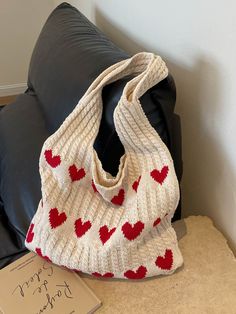 a knitted bag sitting on top of a couch next to a book