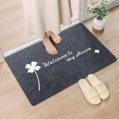 a woman standing on the floor with her feet propped up against a mat that says welcome to my house