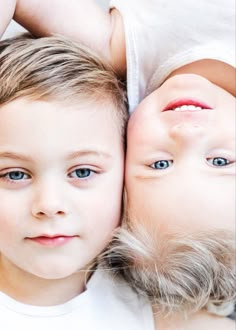 two young children laying next to each other with their heads on one another's shoulders