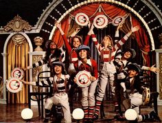 a group of people standing around each other in front of a stage with red curtains