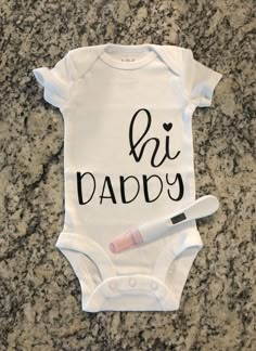 a baby bodysuit with the words di daddy written on it and a toothbrush