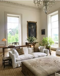 a living room filled with white furniture and windows next to a painting on the wall