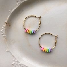 Gold plated hoop earrings with rainbow colored polymer clay accents. Everyday Colorful Beads Polymer Clay Jewelry, Rainbow Dangle Hoop Earrings, Rainbow Nickel-free Dangle Hoop Earrings, Nickel-free Rainbow Dangle Hoop Earrings, Rainbow Hoop Earrings With Ear Wire As Gift, Rainbow Hoop Earrings With Ear Wire For Gift, Rainbow Hoop Earrings For Pierced Ears, Rainbow Hypoallergenic Hoop Earrings, Hypoallergenic Rainbow Hoop Earrings