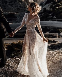 a bride and groom hold hands as they walk through the desert