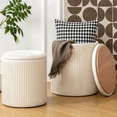 two white stools sitting on top of a wooden floor next to a potted plant