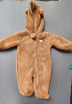 a baby's brown teddy bear onesie laying on top of a laptop computer