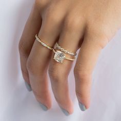 a woman's hand with two rings on it and a diamond in the middle