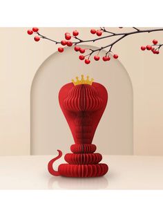 a red vase sitting on top of a table next to a branch with berries hanging from it