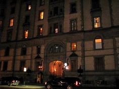 an old building lit up at night with cars parked in front