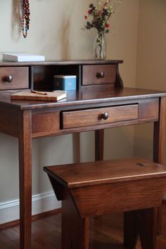 a wooden desk with drawers and a bench in front of it on a hard wood floor