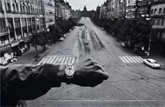 black and white photograph of a man's hand holding onto an electronic watch on a city street