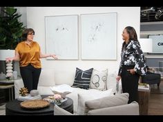 two women talking in a living room with couches and lamps on either side of them