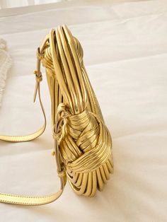 Elevate your style with our luxurious, handcrafted Gold Noodle Bag. This designer handbag features a unique rope-knotted design and a chic, gold color that exudes sophistication. Perfect for an evening out, this medium-sized bag features a secure zipper closure and an adjustable strap for added comfort. Made with high-quality PU leather, this bag is both glamorous and practical, making it a must-have for any fashion-forward woman. 100% Polyurethane Please allow 3-5 business days to process and s Gold Woven Top Handle Straw Bag, Gold Woven Leather Bag For Everyday Use, Gold Luxury Bag With Woven Leather, Luxury Gold Woven Bag, Luxury Gold Straw Bag, Elegant Gold Straw Bag With Gold-tone Hardware, Chic Gold Evening Bag With Adjustable Strap, Chic Gold Straw Bag With Braided Handles, Luxury Gold Shoulder Bag With Braided Handles