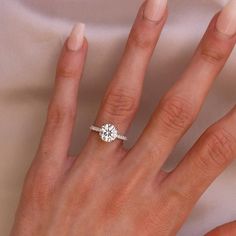 a woman's hand with a diamond ring on top of her finger and the other hand holding an engagement ring