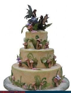 a three tiered cake with fairy figurines on top