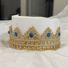 a gold and blue tiara sitting on top of a white tablecloth covered bed