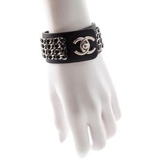 This exceptional secondhand Chanel Turnlock Bracelet is an edgy statement piece that is waiting to upgrade your luxury looks! Composed of black Italian leather, this wide cuff bracelet is adorned by four rows of tonal interwoven leather and aged silver-toned chains. An oversized CC turn-lock clasp closure sits at the center of this piece for easy access and the utmost security. From the French fashion house's Spring 2013 collection, this luxury bracelet is the ultimate collector's item that will Luxury Metal Leather Bracelet, Chic Leather Bracelet For Party, Designer Leather Bracelet, Designer Black Leather Bracelet, Edgy Leather Cuff Bracelet, Luxury Leather Cuff Jewelry, Luxury Black Cuff Bracelet, Luxury Black Leather Bracelet With Palladium Hardware, Black Leather Jewelry With Palladium Hardware