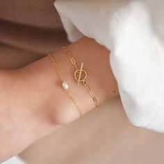 "This bracelet features a small toggle closure on a dainty paperclip gold chain that measure 2 mm wide and can be made to fit your wrist snugly. Toggle measures 9mm wide. Be sure to measure your wrist if you are going for a tight fit like the model who is wearing the 5.75 inches. Otherwise, the standard length at department stores for women's bracelets is 7 inches. This item is 14k gold filled and is tarnish-resistant, water-resistant, and hypoallergenic. --------------------♥ PROMOS ♥---------- Modern Sterling Silver Bracelet With Toggle Clasp Gift, Elegant Sterling Silver Bracelet With Clasp For Gift, Timeless Bracelets With Lobster Clasp For Gift, Timeless Bracelet With Lobster Clasp For Gift, Adjustable Dainty Paperclip Bracelet, Elegant Chain Bracelet With Clasp As Gift, Elegant Charm Bracelet With Toggle Clasp As Gift, Gold Oval Link Oyster Bracelet Gift, Elegant Sterling Silver Bracelet With Toggle Clasp For Everyday