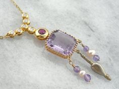 We crafted this one of a kind, unique necklace using pieces from a variety of eras! The center piece is an exquisite amethyst pendant that comes from the Art Nouveau era. We've added pearl and amethyst beads strung on gold wire, and an antique Victorian pendant to the base of this neat piece! The necklace we've chosen to finish this with is contemporary, with bezel set diamonds and a fine, deep red ruby at the center.Metal: 18k Yellow GoldGemstone: Amethyst Gem Measurements: 13.4 x 12.1 mm, Rect Luxury Amethyst Necklace With Gemstone Accents, Luxury Amethyst Pendant Necklace, Luxury Purple Necklaces For Anniversary, Luxury Purple Necklace For Anniversary, Luxury Yellow Gold Amethyst Necklace, Elegant Amethyst Pendant Necklace, Luxury Multi-stone Amethyst Necklace, Luxury Amethyst Multi-stone Necklace, Formal Multi-stone Amethyst Necklaces