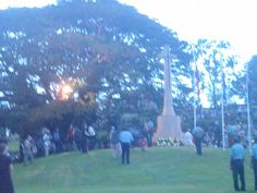 people are standing in the grass near a monument