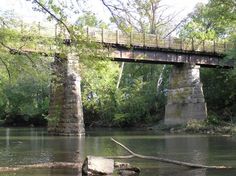 a bridge over a body of water with trees in the foreground and rocks in the foreground