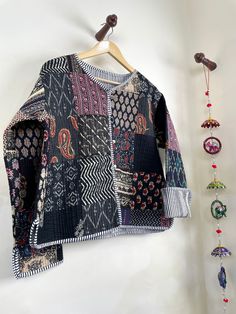 a jacket is hanging on the wall next to some beads and necklaces, as well as an ornament