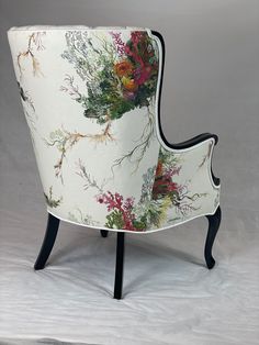 an upholstered chair with flowers on it's back and legs, against a white background