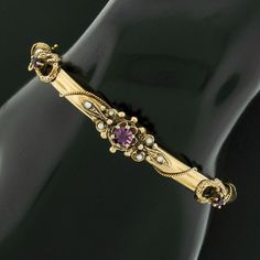 "This fine antique bangle bracelet was crafted from solid 14k yellow gold during the Victorian era. It features 3 old round cut purple stones neatly prong set across its top with the center stone being slightly larger. All three of the stones display a truly gorgeous and well matched deep purple color with lovely shine that brings such an attractive and rich look to this piece. It is further adorned with 6 adorable cultured seed pearls neatly set throughout the center design for a wonderful touc Victorian Gold Wedding Bracelet Stamped 14k, Antique 14k Gold Bangle For Anniversary, Victorian Gold Bracelet For Wedding, Antique 14k Gold Bangle, Victorian 14k Gold Bangle Bracelet, Antique 14k Gold Bracelet For Anniversary, Antique 14k Stamped Bracelets For Anniversary, Victorian 14k Gold Bracelet With 17 Jewels, Victorian Bracelets For Anniversary