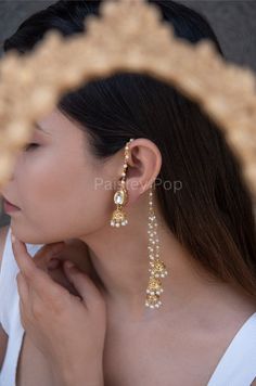 The gold-plated kundan jhumkis are traditionally inspired by the rich Indian Heritage of jewelry making. The design of the bridal jhumkis earrings features pearl hangings and a top encrusted with kundan. These ethnic jhumkis have a gold-plated pearl chain that gives them a delicate and elegant look. The richly traditional design is versatile and can be paired with almost anything Indian.  Closure - Push Back Handcrafted in Jammu and Kashmir  Paisley Pop travels the depths of India to learn techniques and crafts from deep down the local markets and villages. We give utmost importance to our quality and packaging. Our goal is to make sure you receive exactly what you are looking for and for your experience to be a special and memorable one. We are ready to help and advise you through your pu Gold Jewellery Bridal Indian, Simple Indian Earrings, Jhumka Designs Gold Indian, Indian Aesthetic Jewellery, Earrings With Chain Indian, Traditional Earrings Indian Jewelry, Indian Pearl Earrings, Ethnic Jewelry Indian, Indian Bridal Earrings