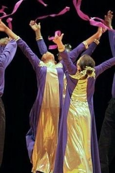 the group of people are dancing together with ribbons in their hands and wearing purple outfits