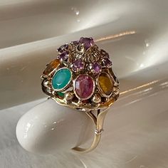 This Art Nouveau Ring Isn't Like Anything We've Seen Before. A Beautiful 14k Gold, Detailed Band Supports An Overstated Setting. The Main Setting Features 9 Small Garnet, And 8 Large Stones Consisting Of; Blue Sapphire, Citrine, Emerald, Ruby, Tiger's Eye, Topaz, Tourmaline, And White Sapphire. Ring Size Is 7 3/4. Weighs 6.8g. Measures 34.925 Mm In Height (Base Of Band To Top Of Setting), 22.225 Mm In Width, 79.756 Mm Circumference. If You Have Any Questions, We Are More Than Happy To Help! Fine Jewelry Multicolor Cabochon Gemstones, Multicolor Cabochon Gemstones Fine Jewelry, Multicolor Cabochon Gemstones For Fine Jewelry, Luxury Multicolor Cabochon Rings, Multicolor Cabochon Rings In Fine Jewelry Style, Multicolor Cabochon Rings Fine Jewelry, Heirloom Multi-stone Yellow Gold Gemstones, Luxury Multi-stone Pink Gemstones, Luxury Pink Multi-stone Gemstones