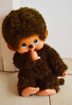 a brown teddy bear sitting on top of a white tile floor next to a door