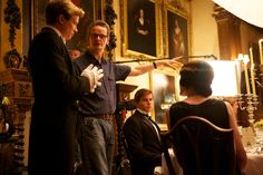 two men and a woman standing in front of a dining room table talking to each other