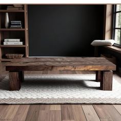 a wooden table sitting on top of a white rug in front of a book shelf