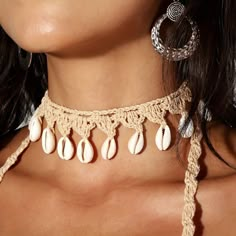 a woman wearing a crochet necklace with seashells hanging from it's sides