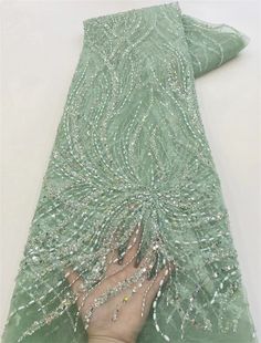 a person is touching the back of a green dress with beadings on it