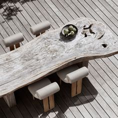 a wooden table with six chairs and a bowl of flowers on it, sitting on a deck